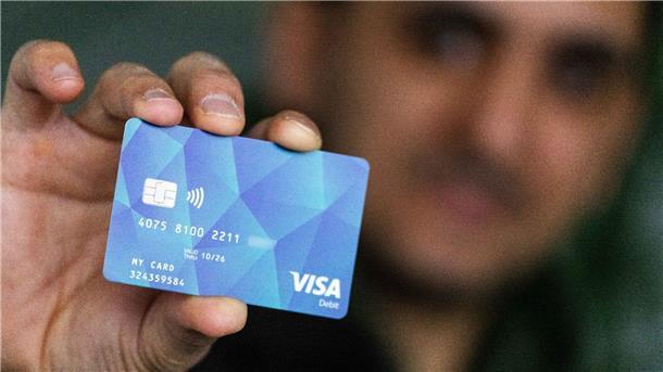 Niedersachsen: Bezahlkarte soll in diesem Jahr starten Ein Geflüchteter hält eine Debitcard in der Hand.
