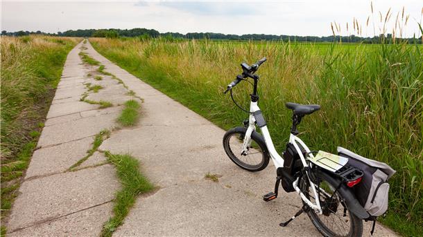 Sanierungsbedürftiger Wirtschaftsweg mit Fahrrad in der Gemeinde Wurster Nordseeküste.
