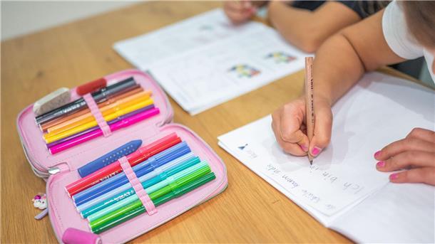 Untersuchungen zeigen Sprachprobleme vieler Kinder Ein Grundschüler und eine Grundschülerin sitzen in einem Wohnzimmer am Tisch und erledigen Schulaufgaben.
