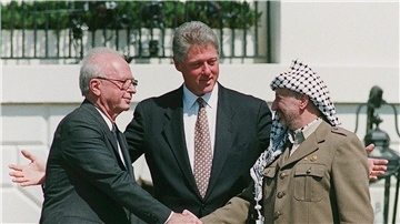 Ein Handschlag, der die Hoffnungen auf einen Frieden zwischen Israel und den Palästinensern symbolisiert: Der damalige Ministerpräsident von Israel, Izchak Rabin (l), und Jassir Arafat (r), damaliger Vorsitzender der Palästinensischen Befreiungsorganisation PLO, geben sich im Beisein von Ex-US-Präsident Bill Clinton die Hand.