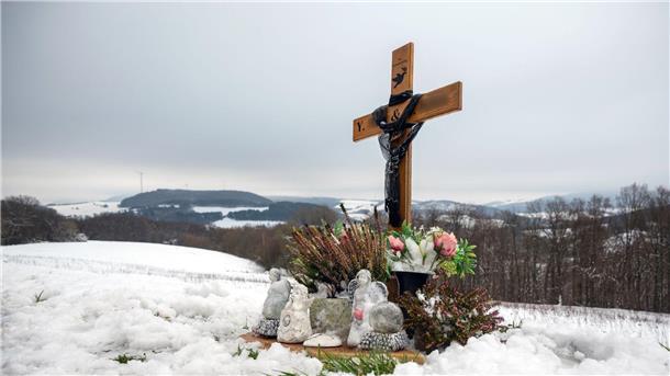 Ein Holzkreuz, Engelsfiguren und Blumen erinnern bei Kusel an die zwei Polizisten, die vor einem Jahr im Dienst getötet wurden.