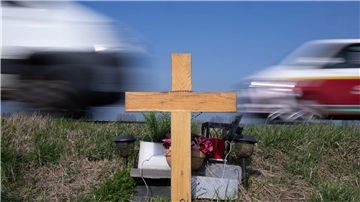 Ein Holzkreuz erinnert an das Opfer eines Verkehrsunfalls.