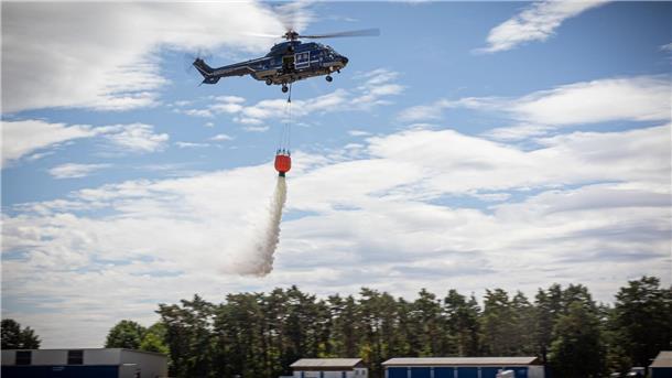 Lösch-Helis statt Flugzeuge – Land sieht sich bestätigt Ein Hubschrauber der Bundespolizei wirft bei einer Waldbrandübung Wasser aus einem Löschwasserbehälter ab.