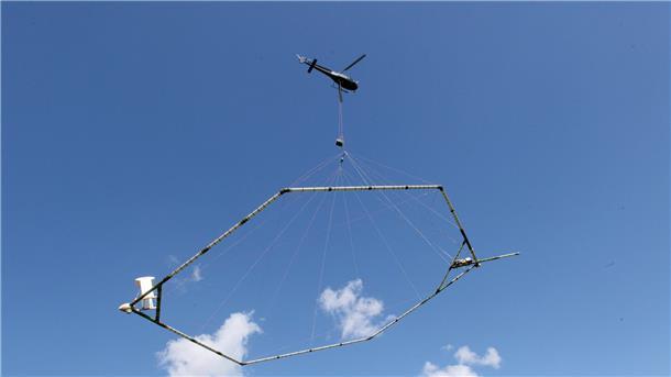 Ein Hubschrauber schleppt eine Antenne über den Grund, die nach dem SkyTEM-Verfahren den Aufbau des Untergrundes misst.
