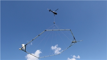 Ein Hubschrauber schleppt eine Antenne über den Grund, die nach dem SkyTEM-Verfahren den Aufbau des Untergrundes misst.
