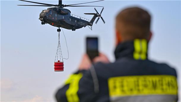 Waldbrände aus Luft löschen: Verband für mehr Flugzeuge Ein Hubschrauber vom Typ Sikorsky CH-53 der Luftwaffe fliegt mit einem Wasserbehälter während einer Übung über den Flugplatz Müncheberg-Eggersdorf.