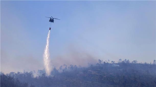 Ein Hubschrauber wirft Wasser auf einen Waldbrand im Norden Athens ab.