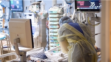Ein Intensivpfleger steht auf der Intensivstation eines Krankenhauses neben einem Covid-19-Patienten.