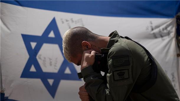 Israel in der Isolation: Zwischen Trotz und Durchhaltewillen Ein israelischer Soldat neben der Nationalflagge: Gibt es für Israel einen Ausweg aus diesem Schlamassel?