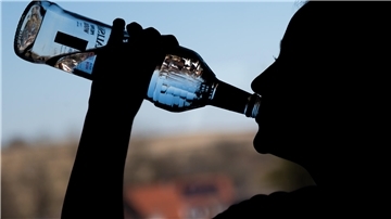 Ein jugendliches Mädchen trinkt in ihrem Zimmer eine Flasche Wodka. 