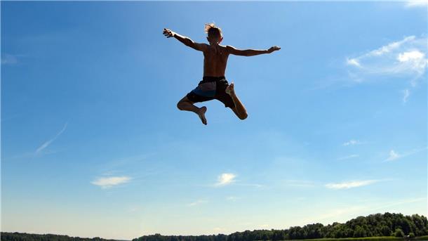 Ein Junge springt in das Wasser eines Sees.