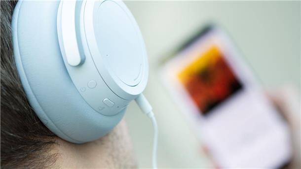 Studie zu Unterhaltungsmusik: Leadgesang leiser geworden Ein junger Mann hört mit Kopfhörern Musik.