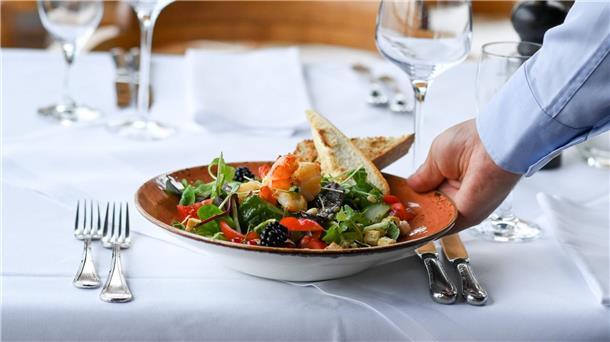 Ein Kellner serviert einen Salatteller in einem Restaurant.