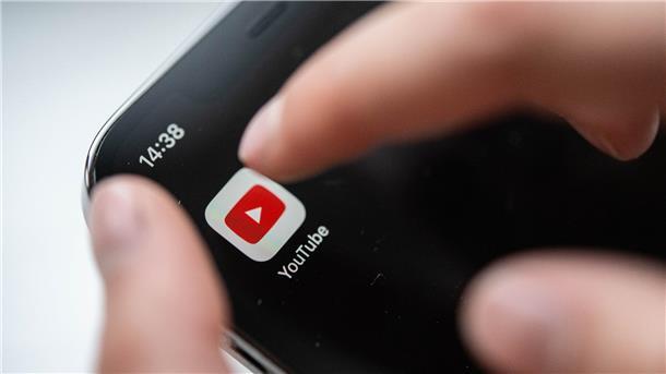 Ein Kind bedient ein Smartphone, auf dem eine Youtube-App zu sehen ist.