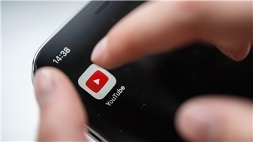Ein Kind bedient ein Smartphone, auf dem eine Youtube-App zu sehen ist.