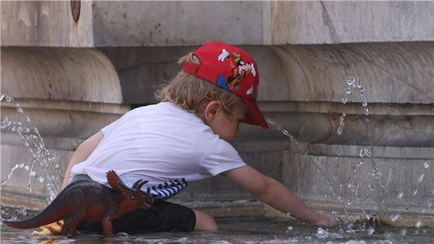 Ein Kind kühlt sich bei 38 Grad Celsius an einem Brunnen ab.
