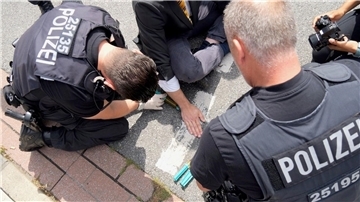 Polizisten um einen Klimakleber