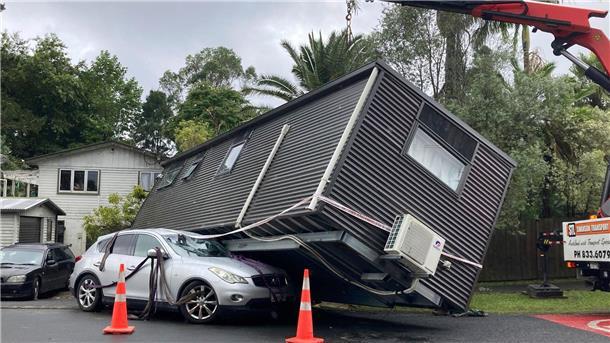Mindestens drei Tote nach Rekordregen in Auckland Ein Kran hebt ein Tiny-House von einem Auto nach massiven Regenfällen in Auckland.