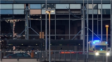 Ein Krankenwagen fährt an der zerstörten Fassade des Terminals des Flughafens Zaventem. (Archivbild)