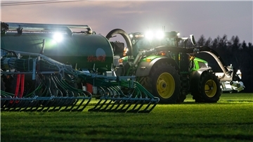 Ein Landwirt bringt mit seinem Gespann Gülle auf einem Feld aus.