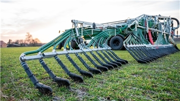 Ein Landwirt bringt mit seinem Gespann Gülle auf einem Feld aus
