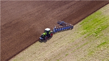 Ein Landwirt pflügt ein abgeerntetes Feld und bereitet es für die Neubestellung vor.