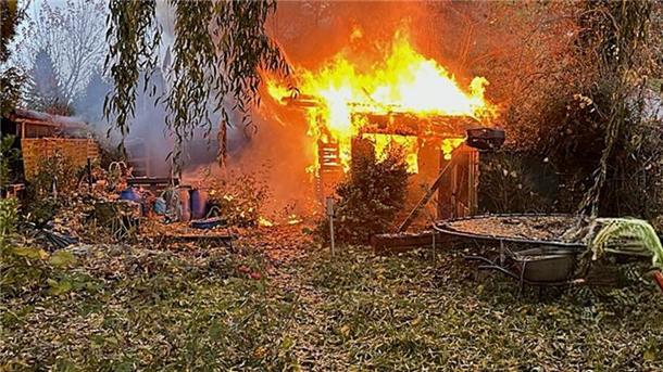 Eine Laube steht in Vollbrand in einem Garten. 