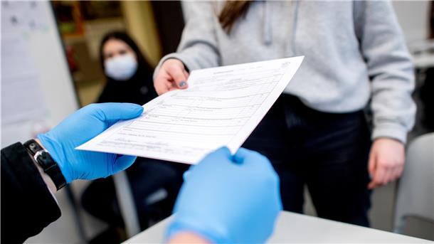 Ein Lehrer verteilt 2021 die Halbjahreszeugnisse an Schülerinnen und Schüler. In Niedersachsen endete am Freitag das erste Schulhalbjahr.