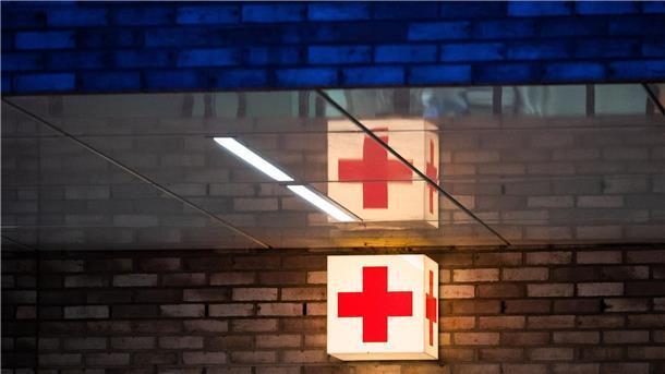 Krankenhausgesellschaft mahnt Kompromisse an Ein Leuchtkasten mit einem roten Kreuz hängt vor der Notaufnahme eines Krankenhauses.