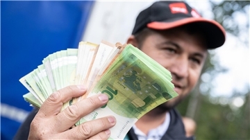 Ein Lkw-Fahrer mit einem Bündel Geldscheinen in der Hand.