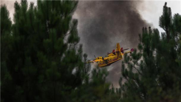 Ein Löschflugzeug überfliegt den Wald während eines Brandes in Frankreich.