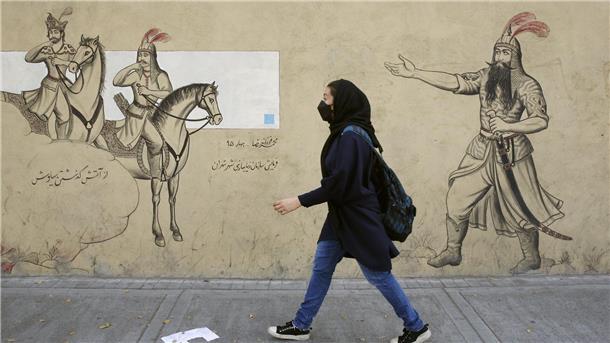 Ein Mädchen geht an einer Häuserfassade in Teheran entlang.