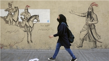 Ein Mädchen geht an einer Häuserfassade in Teheran entlang.
