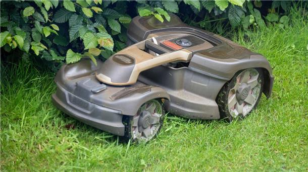 Ein Mähroboter mäht Gras in einem Garten. 