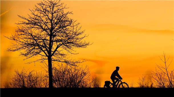 Wetterdienst: Winter zu nass und zu warm Ein Mann fährt bei Sonnenaufgang mit einem Fahrrad über einen Feldweg in der Region Hannover.