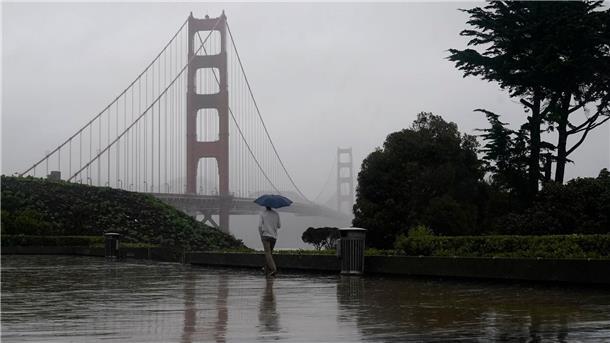 Ein Mann geht bei Regen an der Golden Gate Bridge vorbei, dem Wahrzeichen von San Francisco.