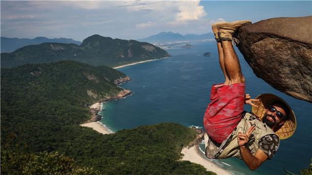 Zum Sterben schöne Fotos? Gefährliche Selfie-Hotspots Ein Mann hängt für ein Bild an dem Felsen „Pedra do Telegrafo“ bei Rio de Janeiro.