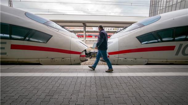Ein Mann läuft über ein Bahnsteig, an dem ein ICE steht.