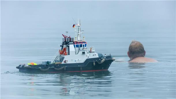 Bilder des Tages Ein Mann schwimmt neben einem Modellboot.