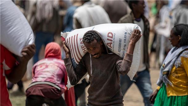 Ein Mann trägt einen Sack Weizen auf den Schultern, der von der Relief Society of Tigray verteilt werden soll.