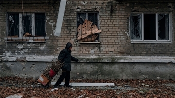 Ein Mann trägt Reisig für einen Holzofen zum Keller eines Wohnhauses im Osten der Ukraine.