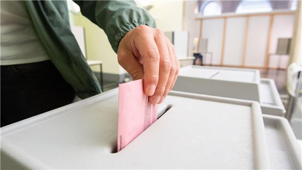 Ein Mann wirft seinen Stimmzettel in eine Urne.