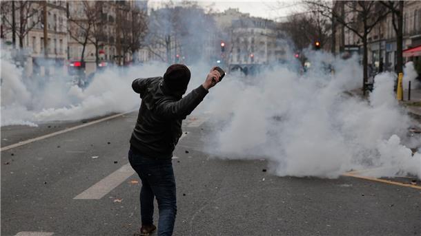 Ein Mann wirft während der Proteste in Paris einen Stein in Richtung von Polizeibeamten.