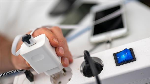 Inflation und Energiekrise: Welche Entlastungen jetzt kommen Ein Mann zieht den Stecker eines Ladegeräts für ein Smartphone aus einer Steckdosenleiste.
