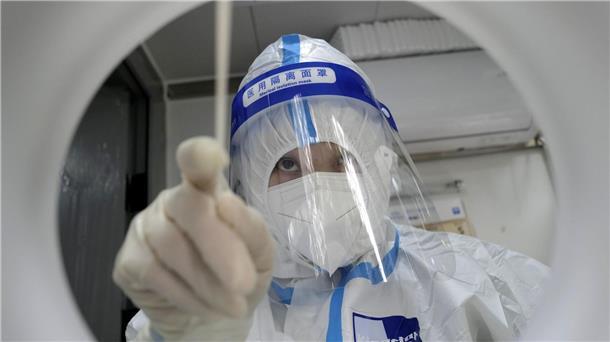 Ein medizinischer Mitarbeiter in Schutzkleidung während er einen PCR-Test zum Nachweis des Coronavirus durchführt.