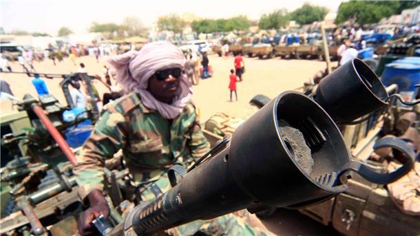 Ein Milizionär sitzt neben militärischer Ausrüstung, die angeblich während eines Gefechts im umkämpften Gebiet in Süd-Darfur erbeutet wurde.
