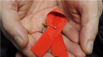 Ein mit dem HI-Virus infizierter Mann mit einer roten Schleife als Symbol der Solidarität mit HIV-Positiven und Aids-Kranken.