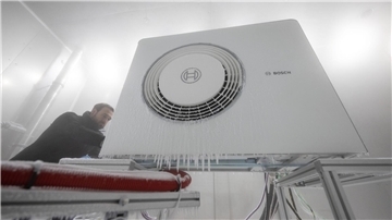 Ein Mitarbeiter der Bosch Thermotechnik GmbH öffnet in einer Klimakammer das Gehäuse einer Bosch-Wärmepumpe.