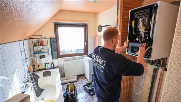 Heizungspläne treffen kriselnden Immobilienmarkt Ein Mitarbeiter einer Sanitär- und Heizungsbaufirma installiert eine moderne Gasbrennwerttherme in einem Einfamilienhaus.