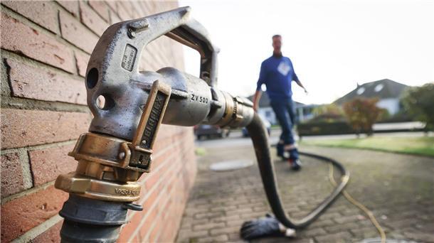 Bremer Haushalte: Beantragung von Härtefallhilfen für Heizöl Ein Mitarbeiter eines Diesel- und Heizöl-Unternehmens geht zur Zapfpistole an einem Füllstutzen für die Heizöllieferung an einen Kunden in einem Einfamilienhaus.